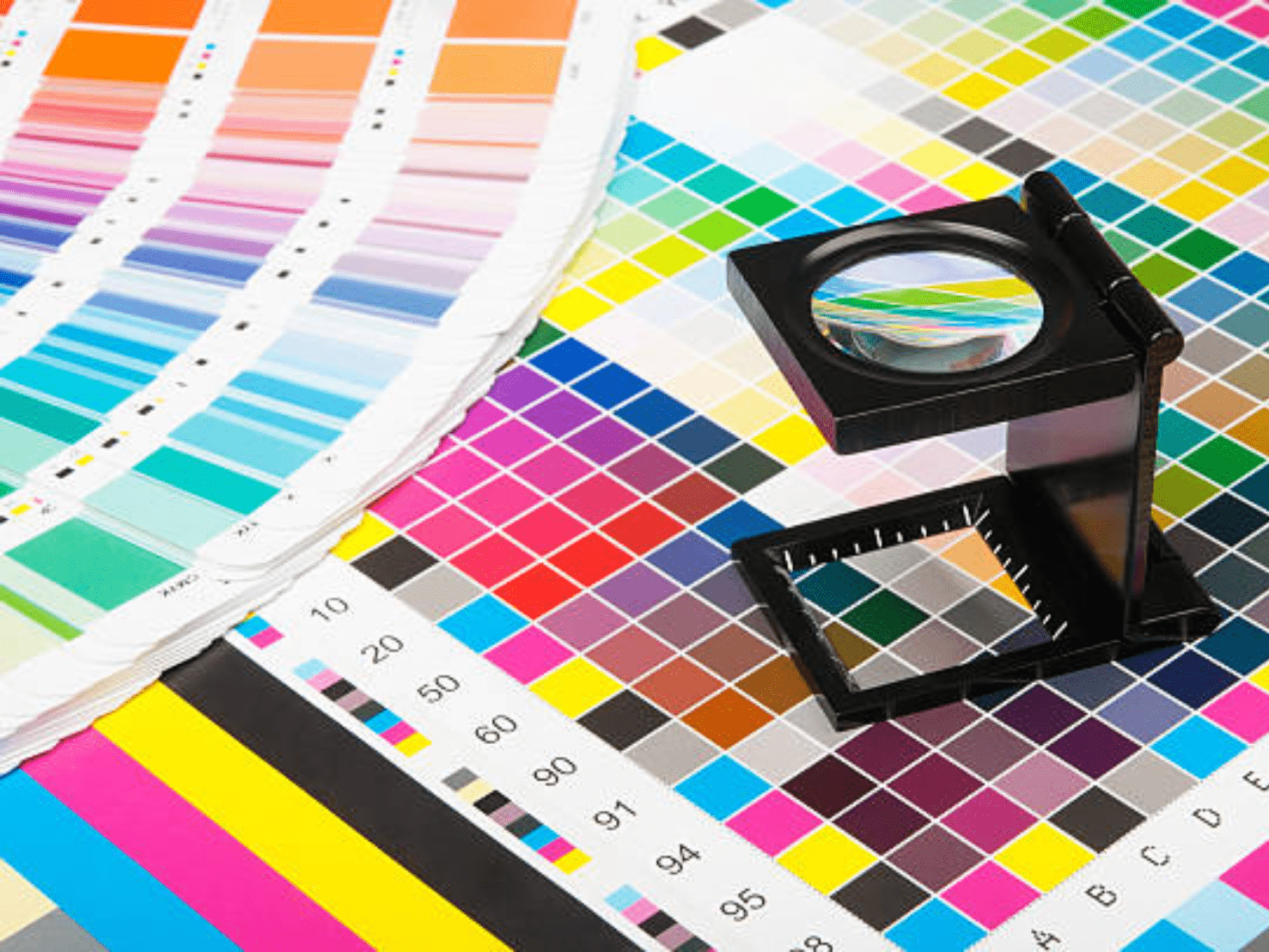 แว่นขยายสีดำวางบนชาร์ตตัวอย่างสีสดใสในงานพิมพ์อิงค์เจ็ท