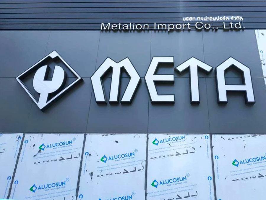 ป้ายโลโก้ meta สีขาว 3D บนผนังอาคารสีเทาเข้ม