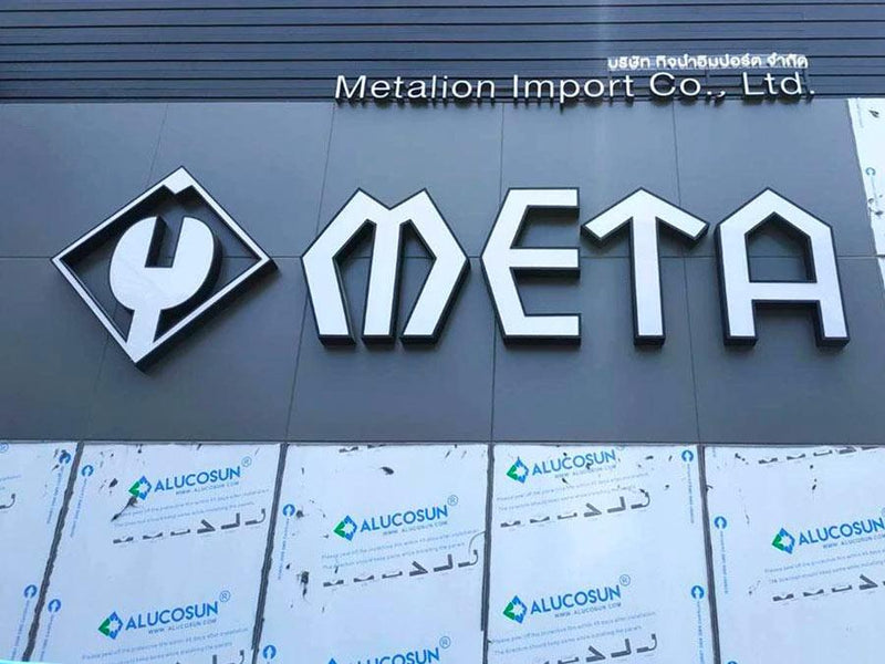 ป้ายโลโก้ meta สีขาว 3D บนผนังอาคารสีเทาเข้ม