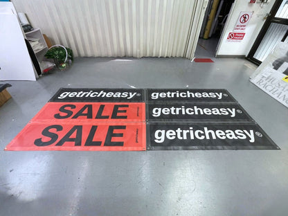 ป้ายไวนิลตาข่ายโปรโมชัน getricheasy สีแดงดำวางบนพื้น