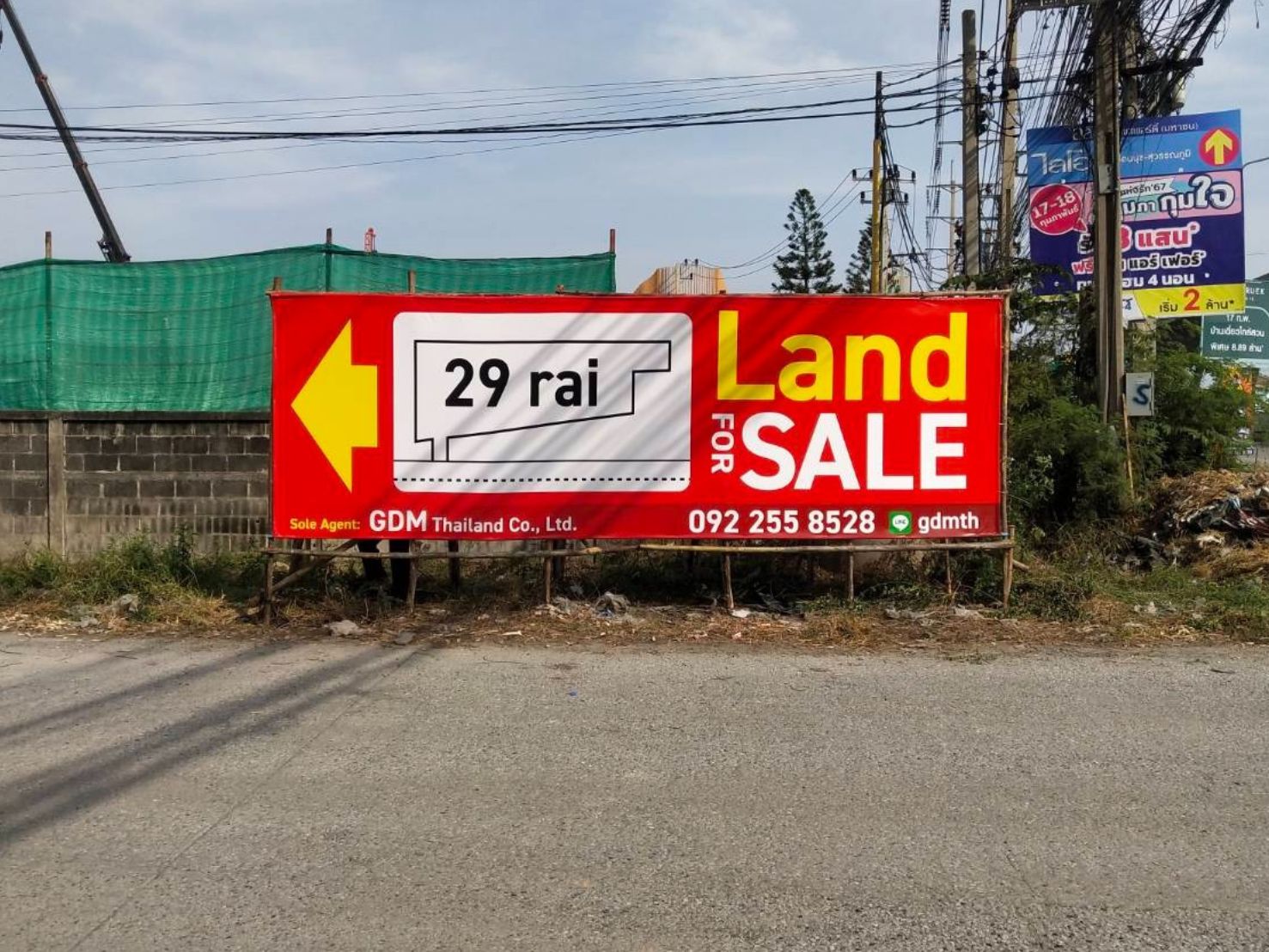 ป้ายไวนิลขึงโครงไม้ สีแดงโฆษณาขายที่ดิน ลูกศรเหลืองตัวอักษรขาว