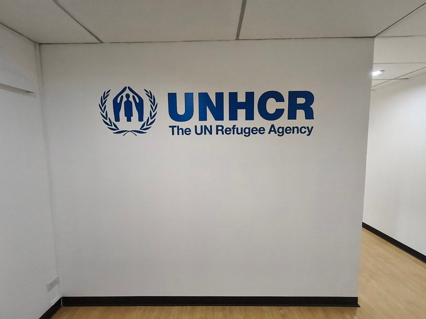 สติ๊กเกอร์ไดคัท UNHCR โลโก้สีน้ำเงินบนผนังขาว