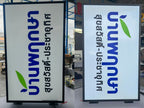 ป้ายไฟอะคริลิค LED ขาวตัวอักษรไทยน้ำเงินใบไม้เขียวกรอบดำติดยื่นผนัง