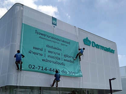 ป้ายไวนิลตาข่าย สีฟ้าเขียว พิมพ์ข้อความไทยและโลโก้ Dermaster