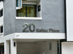 ป้ายคอนโดมิเนียมเงินเมทัลลิกแสดง 20 Salsa Place บนผนังเทา