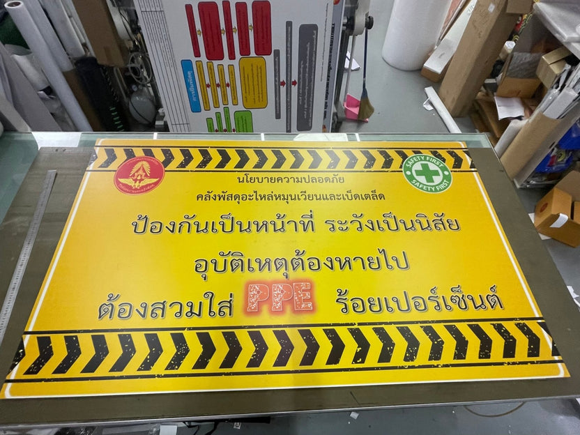 ป้ายเตือนความปลอดภัยสีเหลืองลายเส้นดำ ข้อความไทยตัวหนา โลโก้แดงมุมซ้ายบน