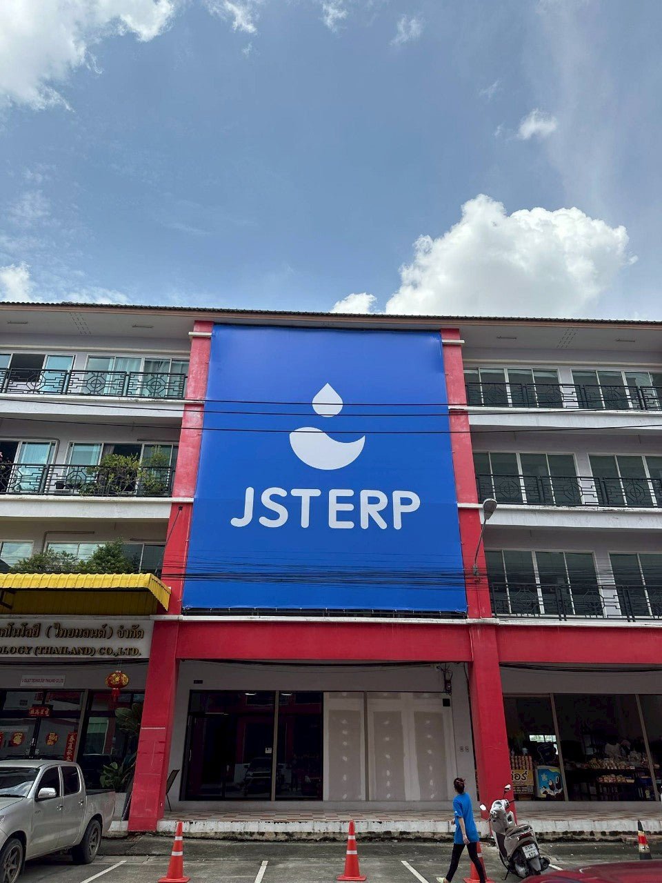 ป้ายไวนิลอิงค์เจ็ทสีน้ำเงินโลโก้ขาวติดอาคารแดง