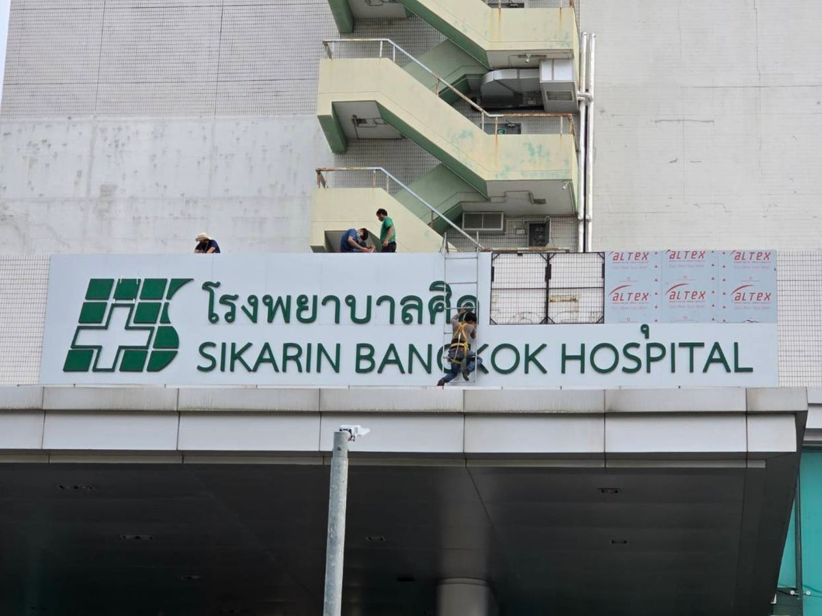 ภาพทีมงานติดตั้งป้ายหน้าอาคาร โรงพยาบาลศิครินทร์ กรุงเทพฯ ในเวลากลางวัน